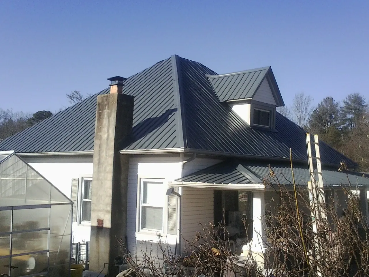 Dark blue standing seam metal roof on a white farmhouse with dormer — Slate & Tile Roof Repair by Roofing Brothers in Scarborough