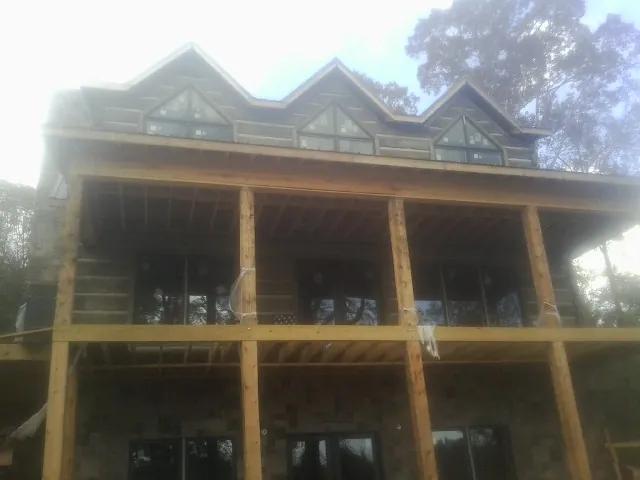 Dormers and porch framing on a large log home under construction — Roof Coating work by our crew in Scarborough