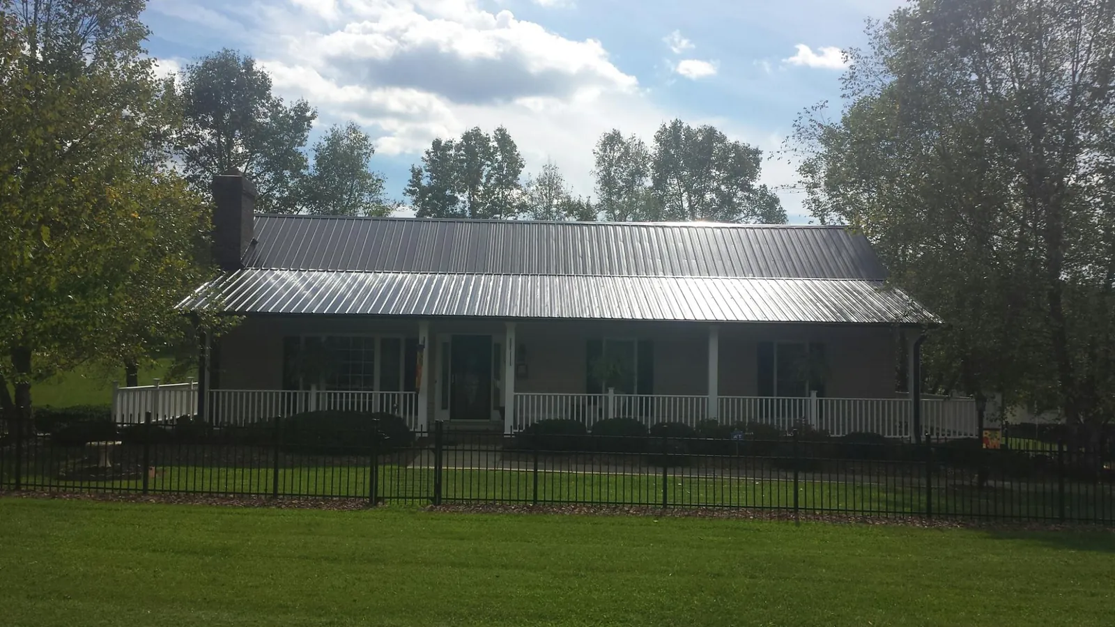 Gray metal roof on a brick ranch with a full width front porch — Gutter Guard Installation work by our crew in Scarborough