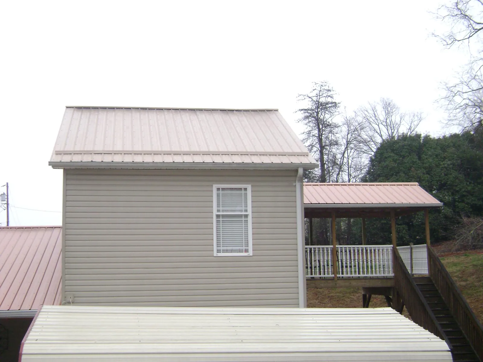 Tan metal roofs on a two story addition and attached porch, from a Roof Replacement job in Scarborough