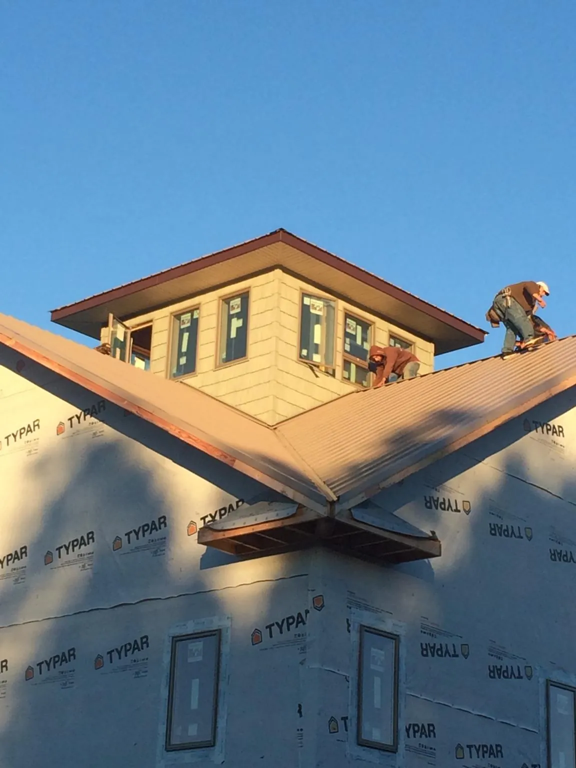 Roofers working around a rooftop cupola on a new metal roof at sunset — Roof Waterproofing in Scarborough by Roofing Brothers
